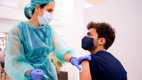 Una farmacéutica vacuna a un colegiado del COFM en la campaña de vacunación 2021